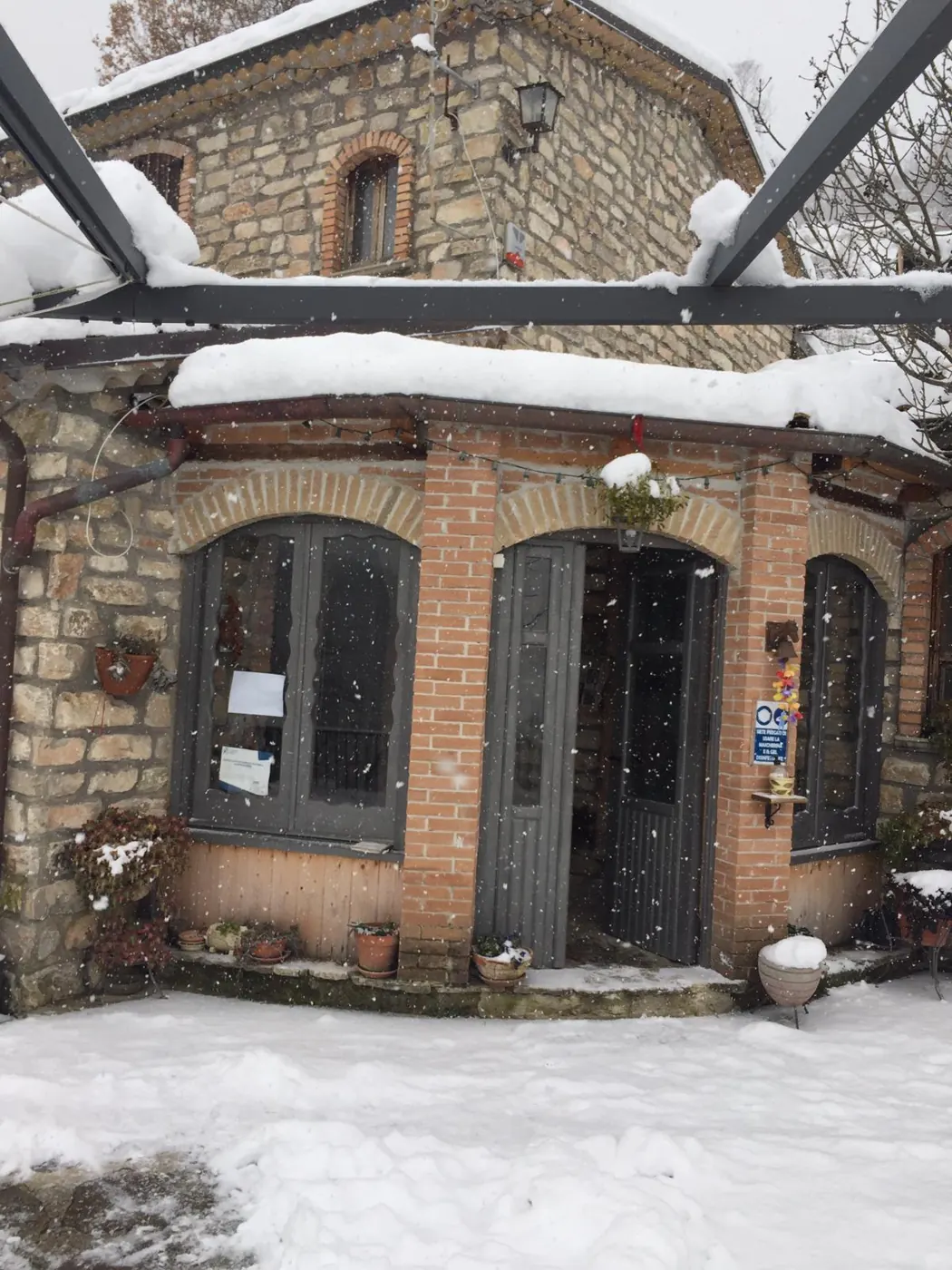 Ingresso del casolare con archi in mattoni e pietra, coperto di neve